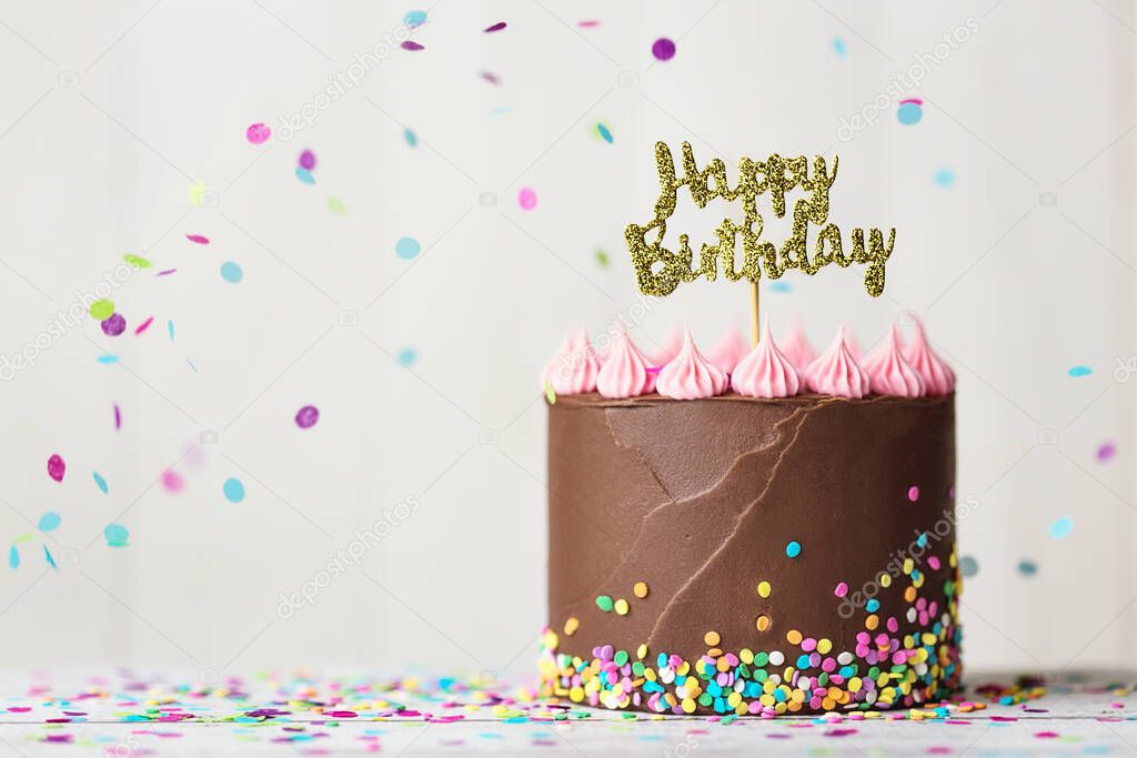 Chocolate birthday cake with happy birthday banner and falling confetti