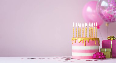 Pink birthday cake with golden candles and balloons clipart