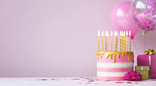 Розовый торт с золотыми свечами и воздушными шарами
