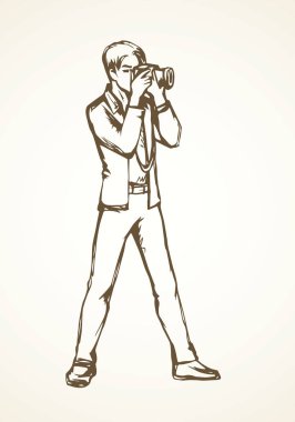 Genç kameraman adam beyaz zemin üzerinde anlık görüntü oturum yapmak. Anahat siyah mürekkep elle çizilmiş slr lens simgesini işaret yarım yamalak retro sanatsal doodle karikatür tarzı tükenmez kalemle kağıt alanı metin için resim
