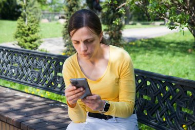Yalnız başına oturan genç bayan, heyecanlı ve mutsuz duygular içinde olduğunu düşünüyor. Çalışma koltuğu, bahar kenti çimen ağacı, doğa, metin alanı. Aşk yüzü bak el üzgün şok bekle eğlence dinleniyor komik rahatla harika tutum