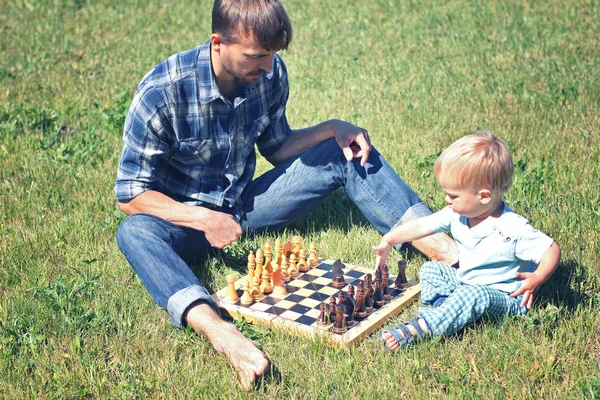 チェスをプレイする彼の子供を教えています お父さんと息子の時間を一緒に屋外 — ストック写真