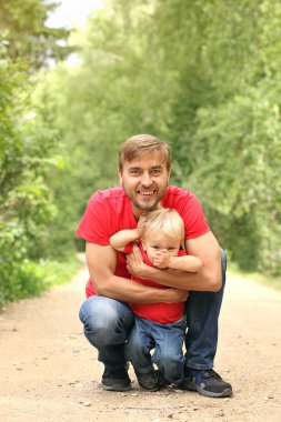 Baba ve onun yürümeye başlayan çocuk evlat fave eğlenceli yaz parkta. Baba sarılma oğlu açık. Aile giyim bak. Kopya alanı.