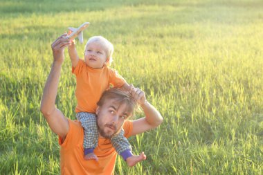 Baba ve yürümeye başlayan çocuk oğlu oyuncak uçak ile yaz sahada oynuyor. Çocukluk veya aile seyahat kavramı. Kopya alanı.
