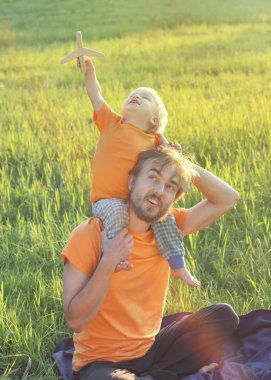 Baba ve yürümeye başlayan çocuk oğlu oyuncak uçak ile yaz sahada oynuyor. Çocukluk veya aile seyahat kavramı. 