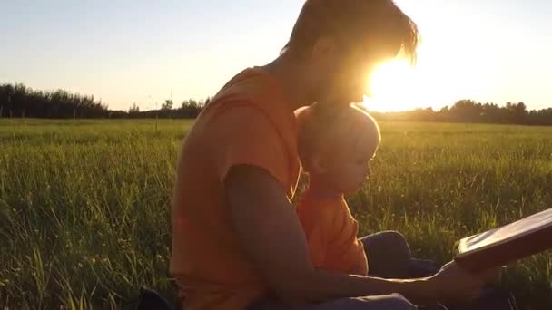 父と息子のかわいい夏の畑で一緒に本を読む感情的に 子育ての概念 ライブ カメラ スローモーション — ストック動画