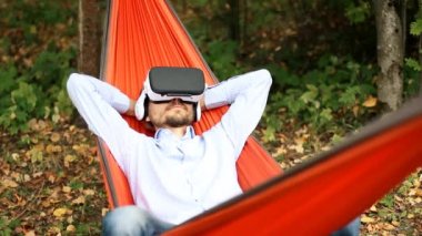 Vr gözlüklü hamakta oturan rahat suni adam sonra çıkarın ve yorgun gözlerini ovuyor. Sanal gerçeklik ya da geleceğin teknolojisi kavramı.