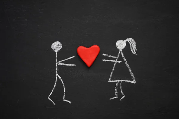 Chalk drawing man and woman holding together volumetric red heart. Blackboard or chalkboard background. Love, relationship, attraction concept. Flat lay.