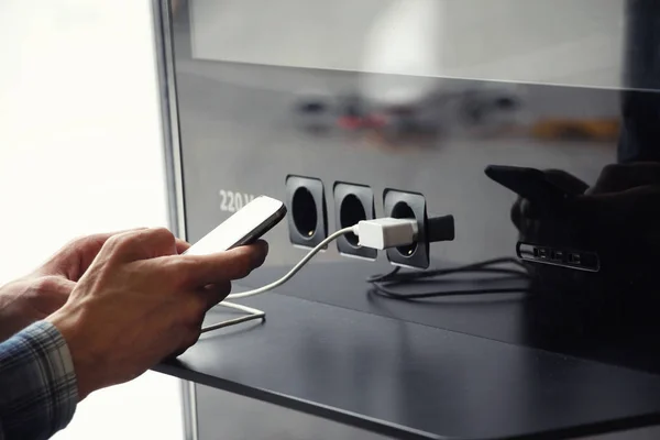Havaalanı genel şarj cihazı ve adamın elleri ile smartphone. Uçak yansıması. Yolculukta aygıt kullanma. 