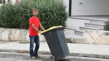 Aile çalışması, baba ve oğul Sokak temiz tutun. Baba taşıyan tekerlek üzerinde büyük bir çöp kutusu çöp içine koymak için onun çocuk yardımcı olur. Ekoloji kavramı. 