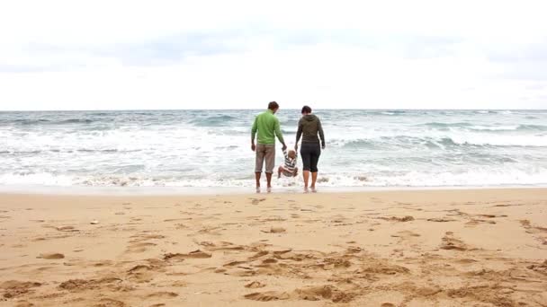 淡季的家庭假期 爸爸妈妈把儿子抱在怀里 站在狂风暴雨的大海中 — 图库视频影像