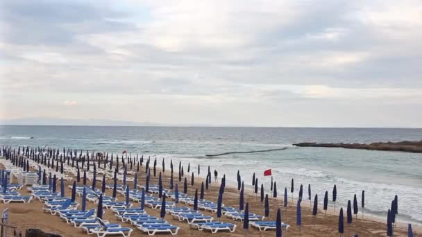 空海滩有紧闭的雨伞 折叠的日光浴床和狂风暴雨的大海 红旗警告危险 禁止游泳 — 图库视频影像