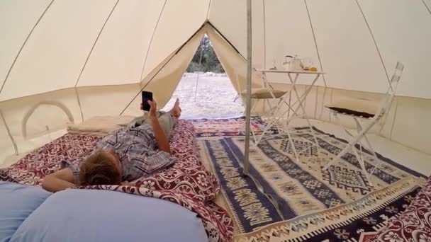 Glamping Buiten Accomodatie Toeristische Mannen Met Smartphone Liggend Bed Binnen — Stockvideo