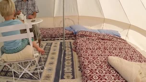 Glamping 屋外の休暇 父と息子の幼児は 居心地の良いインテリアと大きなキャンプ テントの中お茶を飲みます 森の中に豪華な旅行の宿泊施設 外にカメラ移動 — ストック動画