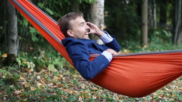 Jovem Homem Negócios Sorrindo Falando Smartphone Relaxando Uma Rede Livre — Vídeo de Stock