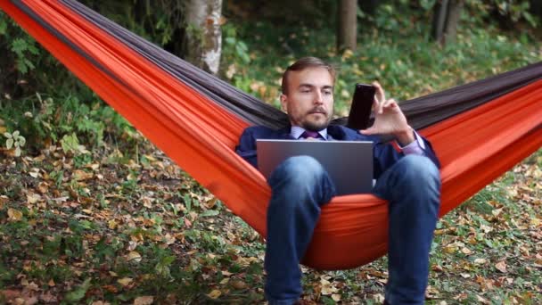 Geschäftsmann Der Mit Laptop Und Smartphone Arbeitet Während Einer Hängematte — Stockvideo