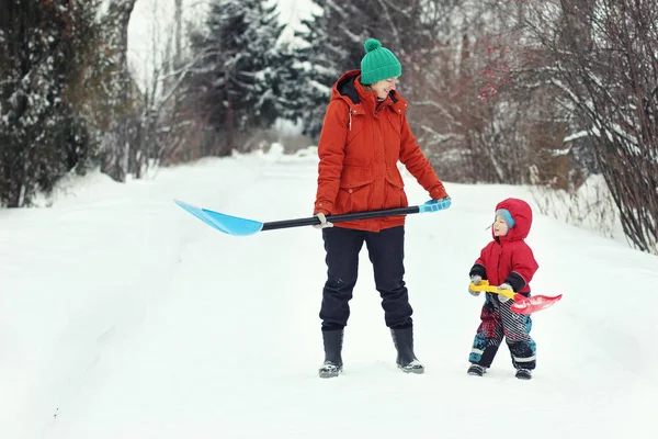 若い母親と幼児の息子は 田舎道に雪のシャベルで立っています 冬の季節の概念 — ストック写真