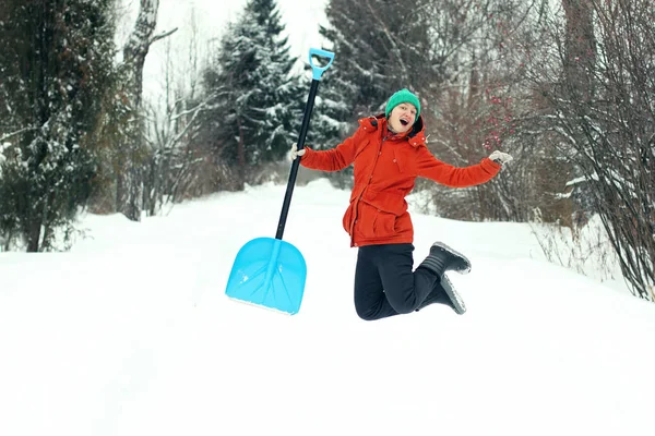 面白いの若い女性は 田舎道に雪のシャベルでジャンプします 冬の季節の概念 — ストック写真