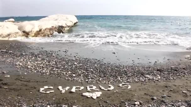 著名的地标总督的海滩与黑色的沙子和白色的岩石 从水边的石头上刻塞浦路斯字 — 图库视频影像