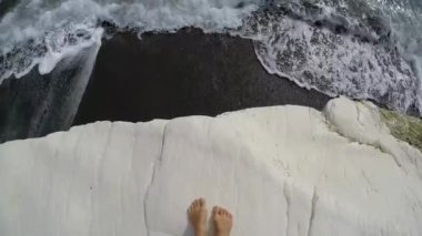 Kadın ayakları üzerinde siyah kum, Kıbrıs'ın Simgesel Yapı ile ünlü Vali sahilde beyaz rock. POV, ağır çekim.