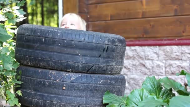 古い車のタイヤで遊ぶかわいい幼児金髪の少年 リサイクルの概念 — ストック動画