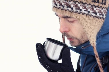 Yakışıklı sakallı uzun yürüyüşe çıkan kimse adam sıcak giysiler içinde termos beyaz zemin üzerine gelen bardağa çay içmek. Sezon kavramı.  