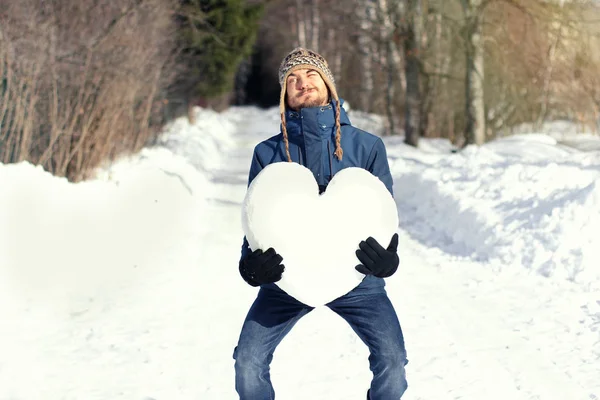 Homem engraçado com grande dificuldade segurando enorme coração feito de neve , — Fotografia de Stock