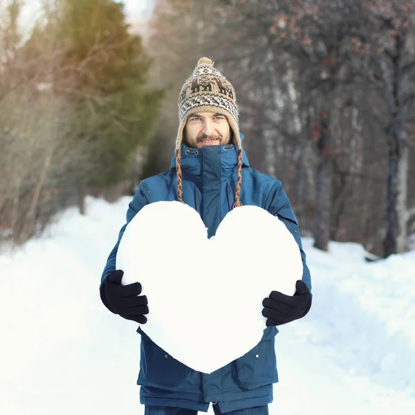 Привабливий бородатий чоловік тримає величезне серце зі снігу, Станді — стокове фото