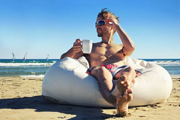 Przystojny mężczyzna na letnie wakacje. Roku spoczywała na pufę na plaży wit — Zdjęcie stockowe