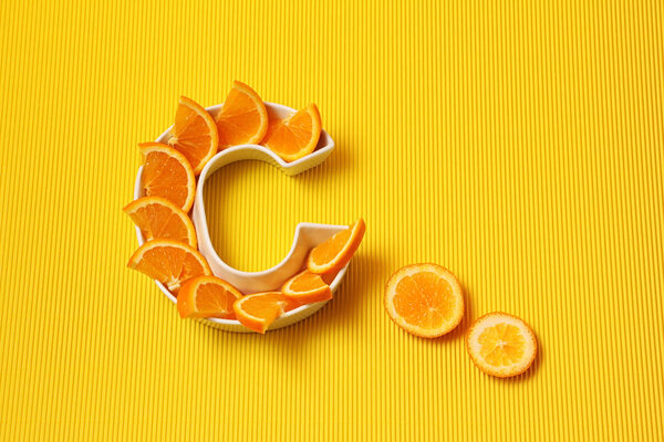 Vitamin C in food concept. Plate in shape of letter C with orang