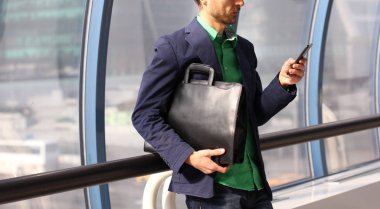 Trendy deri çanta ve hücre fon ile gündelik aşınma işadamı