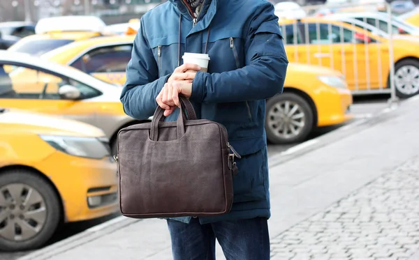 Businessman in casual jacket with leather bag and cup of coffee
