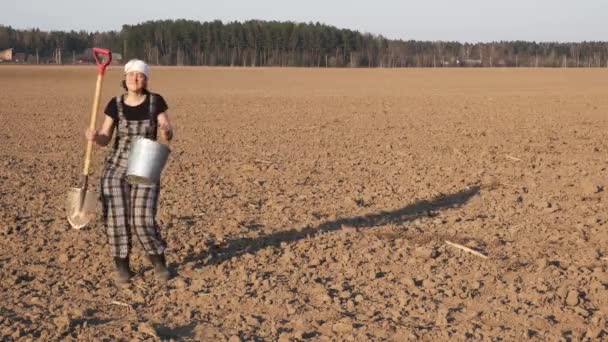 快乐有趣的女农民用铲子和桶跳舞在日落时新犁的田野 — 图库视频影像