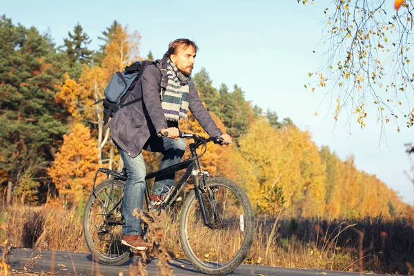 Hombre hipster guapo en ropa casual con mochila a caballo bicicleta en el parque de otoño o el bosque. Descubrimiento hermosa temporada de otoño —  Fotos de Stock