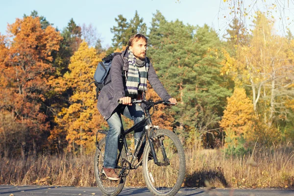 Hombre hipster barbudo guapo en ropa casual con mochila a caballo bicicleta en el parque de otoño o el bosque. Descubrimiento hermosa temporada de otoño —  Fotos de Stock