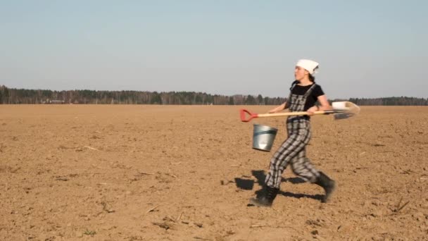 乡村的幸福生活 有趣的成年女农民用铲子和桶跳新鲜犁的田地 慢动作 — 图库视频影像