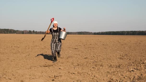 滑稽的樱桃女农跑过犁地跳向一边铲和桶 慢动作 — 图库视频影像