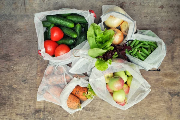 Fresh organic vegetables, fruits and greens in reusable recycled mesh produce bags on wooden background. Zero waste shopping concept. No single-use plastic. — Stock Photo, Image