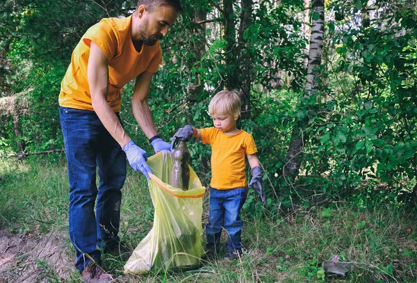 Des bénévoles ramassent des déchets dans le parc. Père et son fils tout-petit nettoyer la forêt pour sauver l'environnement de la pollution . — Photo