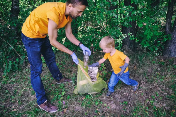 Ayah dan anak secara sukarela mengumpulkan sampah plastik di alam untuk menyelamatkan lingkungan dari polusi . — Stok Foto