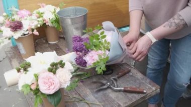 Moskova, Rusya - 25 Mayıs 2019: Eldeki dövmeli kadın çiçekçi taze bahar çiçeklerinden buket yapımı.