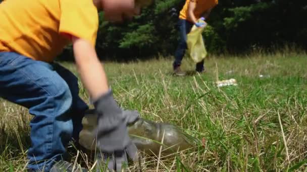 ボランティアが公園でゴミを拾う 父と彼の幼児の息子は森を掃除します 小さな男の子は 汚染から環境を保存するために自然にプラスチックゴミを収集します — ストック動画