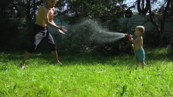 Lindo Niño Rubio Padre Jugando Con Aspersor Jardín Patio Trasero — Vídeo de stock