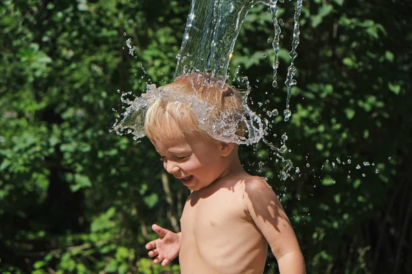 Pequena criança bonito é derramado com água fria do balde. Jogos de água no dia quente de verão no quintal. Endurecimento para a saúde. Fortaleça seu corpo. Manter a calma . — Fotografia de Stock