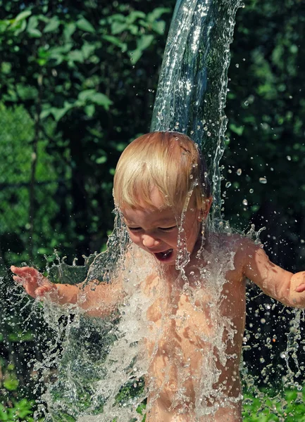 Little boy is poured with cold water from bucket. Kids water games on hot day in backyard. Hardening for health. Strengthen your body. Staying cool in summer. — Stock Photo, Image