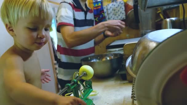 フルーツドライヤーでリンゴチップを作るためのメカニックピラーでリンゴを切る台所で父と彼の幼児の息子 — ストック動画