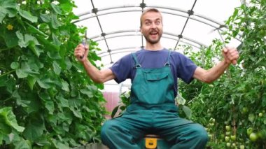 Serabahçe ekipmanları ile yakışıklı genç sakallı çiftçi portresi. Mutlu bahçıvan onun büyüyen bitkiler gösterir.