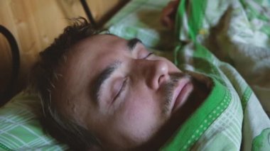 Yakın çekim, yakışıklı sakallı adam yatak odasında yatakta sabah erken kalkar.