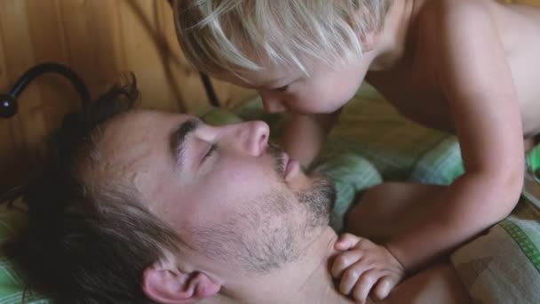かわいい幼児の男の子は寝室で彼の父親を目覚め 息子は早朝にパパにキスをした 幸せな家族の瞬間のライフスタイル — ストック動画