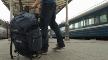 Turist sırt çantasını koyar ve tren istasyonu platformunda, tren, kalkış veya varış bekliyor gider. Seyahat konsepti.